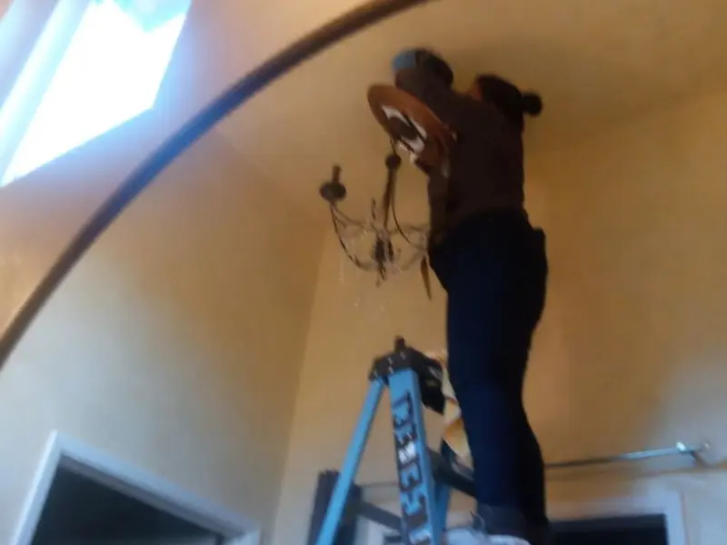 Electrician installing a chandelier in a Charlton residence